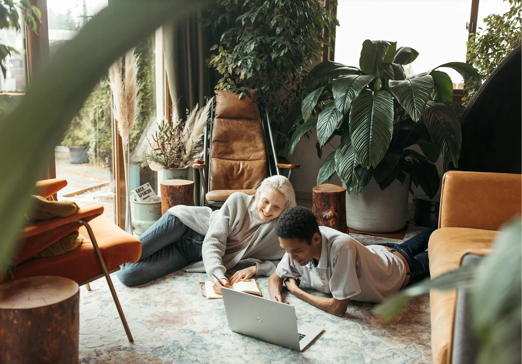 Two people relaxing on the floor at home while using a laptop